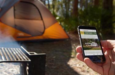 hand holding an iphone making camping reservation