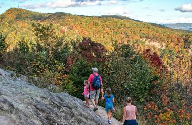 Family hiking on rock outcropping among fall folliage