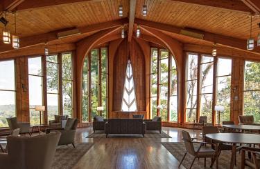 lobby of General Butler SRP lodge in rich golden wood and arched windows showing pine trees