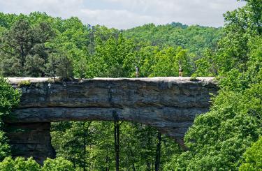 the sandstone natural Bridge in the distance with people walking over it in Summertime