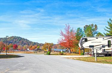 blue sky day with vibrant fall colors; rv inforeground and playground and lake in distance