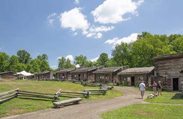 blue skies over interior of fort showing connected log cabins and guests walking